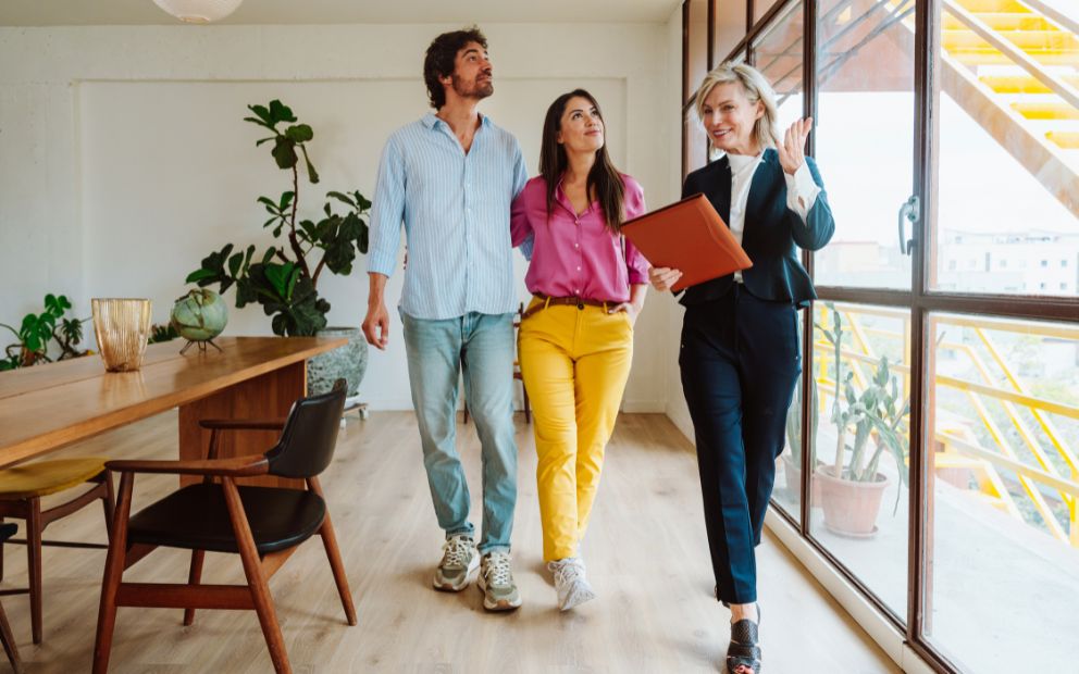 Man and woman couple touring home with realtor and discussing multiple offers on a house