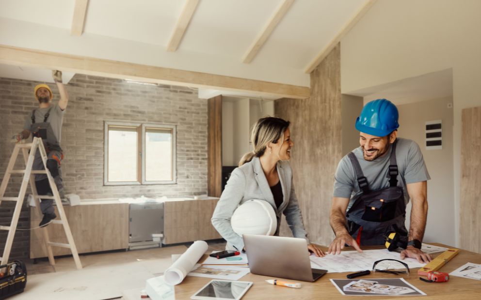 Woman speaking with builder inside home mid-construction after asking is it too late to build a home