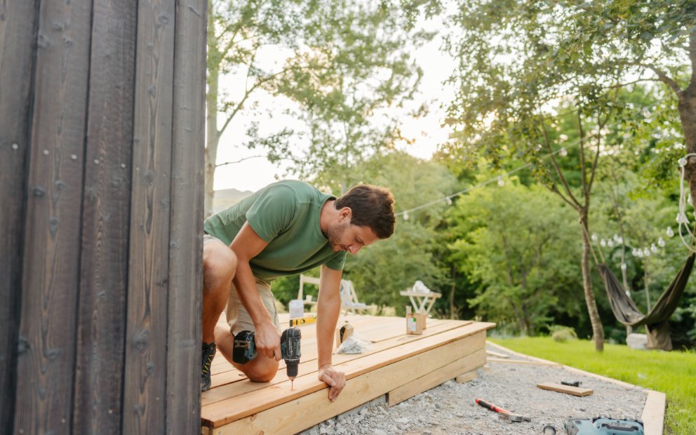 Man working on his back porch after researching deck vs patio
