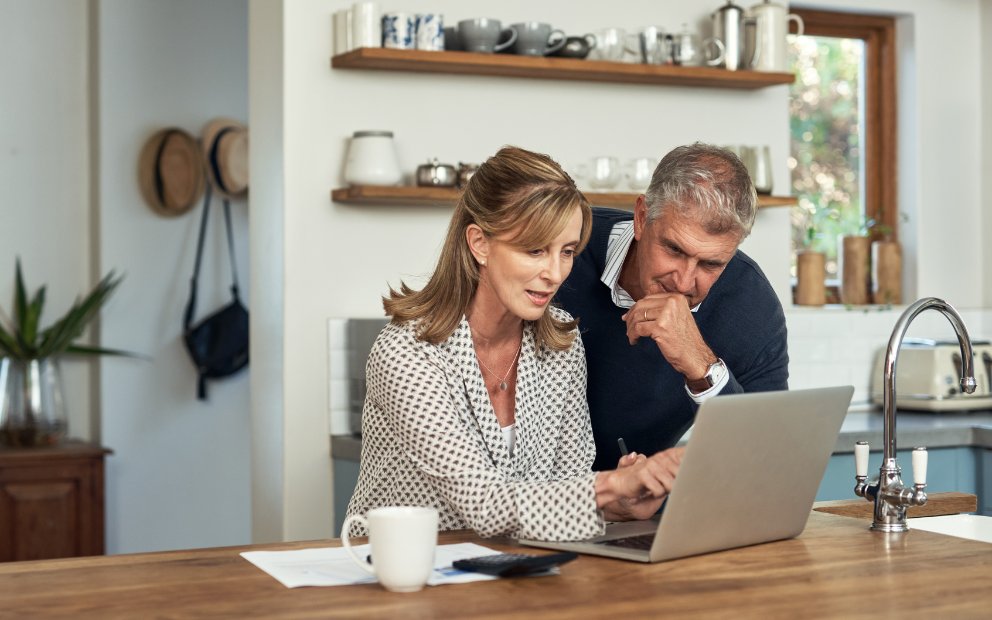 Middle-aged man and woman couple reviewing home equity and your mortgage on laptop