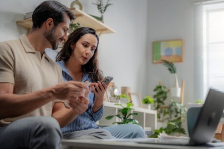 Man and woman couple sitting at home together while they discuss a recast vs refinance conventional loan