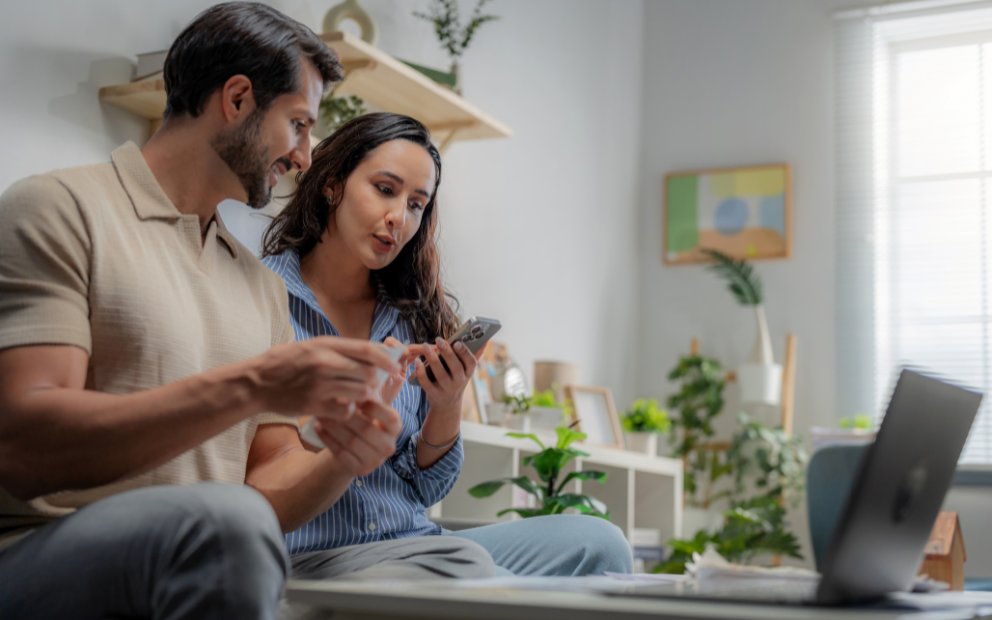Man and woman couple sitting at home together while they discuss a recast vs refinance conventional loan
