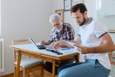 Young adult man reviewing va loan gift funds with elderly male family member