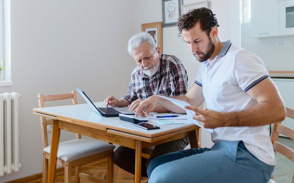 Young adult man reviewing va loan gift funds with elderly male family member