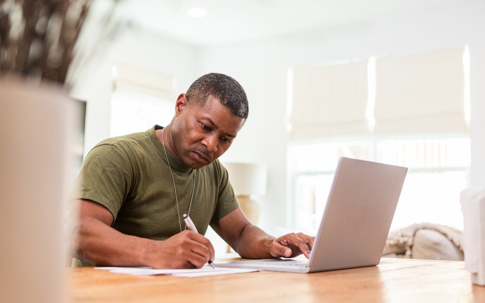 Middle-aged veteran man researching VA loan questions at home on laptop