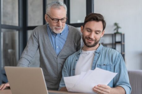 Older man looking over fha gift funds paperwork with his adult son at home