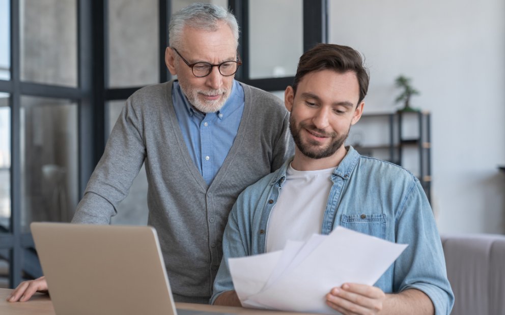 Older man looking over fha gift funds paperwork with his adult son at home