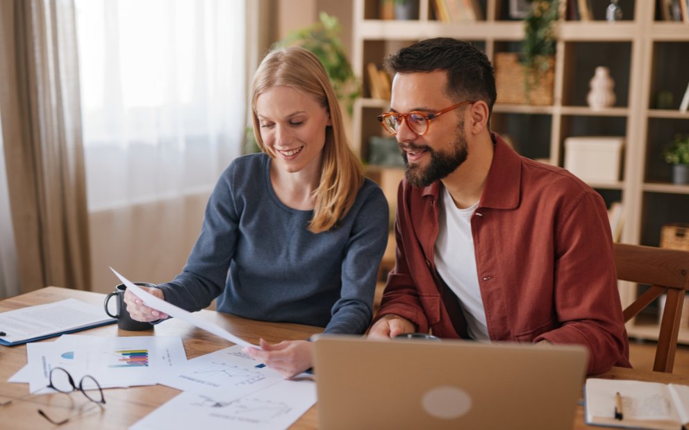 Young man and woman couple reviewing online how to prepare to buy a home