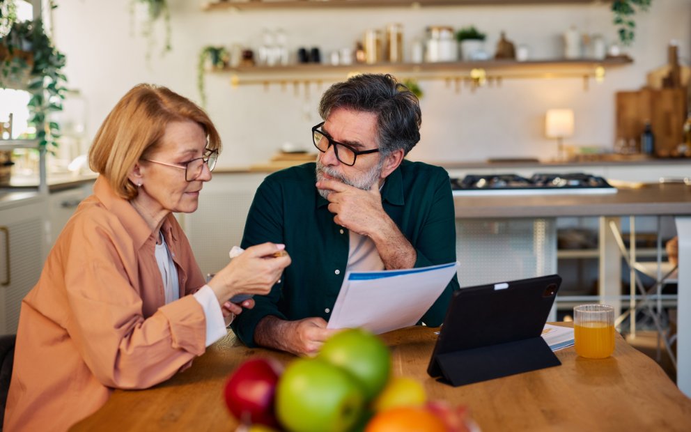 Older mand and woman couple sitting in home kitchen together discussing using equity