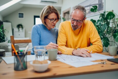 Older mand and woman couple sitting at home reviewing HELOC vs. home equity loan for renovation