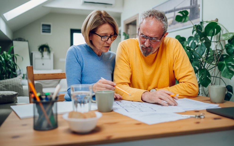Older mand and woman couple sitting at home reviewing HELOC vs. home equity loan for renovation