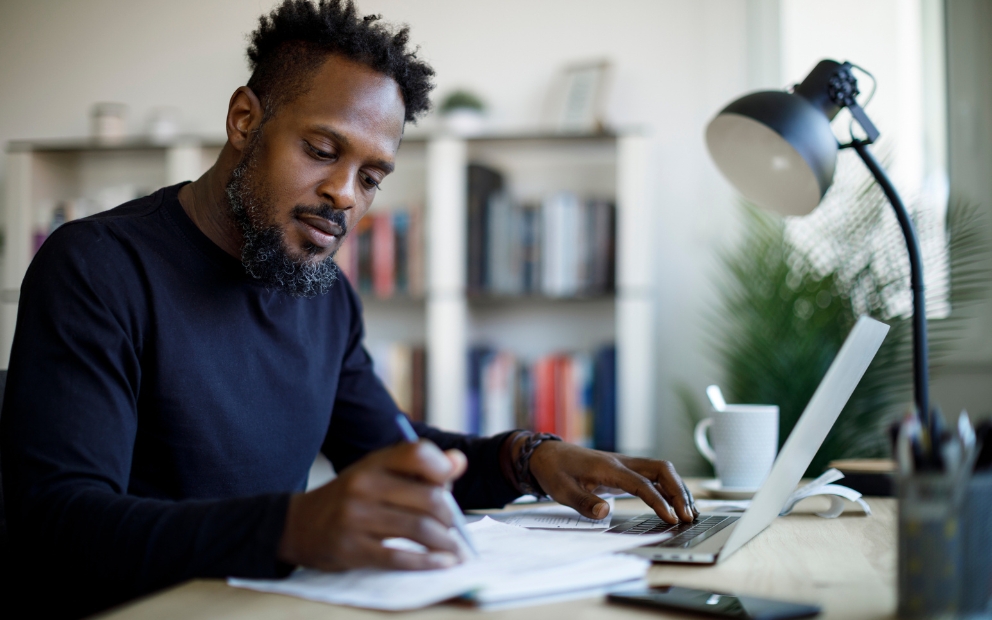 Adult man sitting at home desk researching questions to ask before buying a rental property