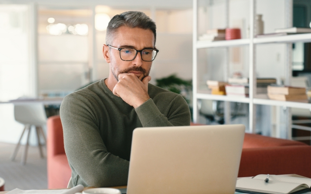 Middle-aged man at home researching VA loan down payment on laptop