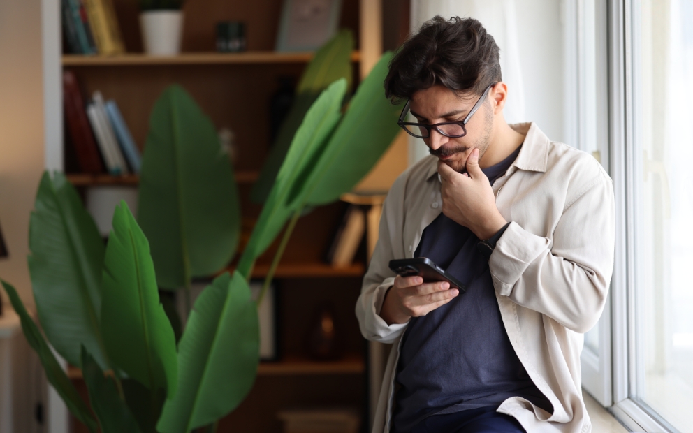 Young man looking on phone to see what happens when mortgage rates drop after buying a house